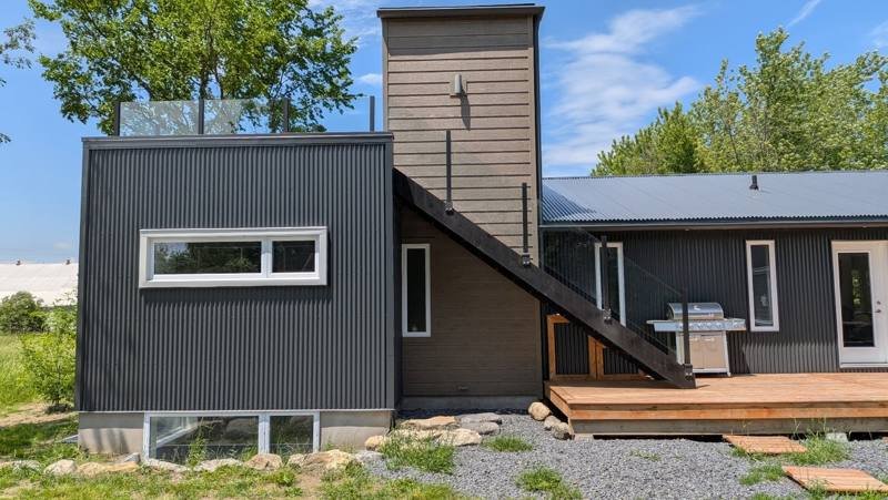 Modern home finished in dark vertical steel cladding with a cedar deck