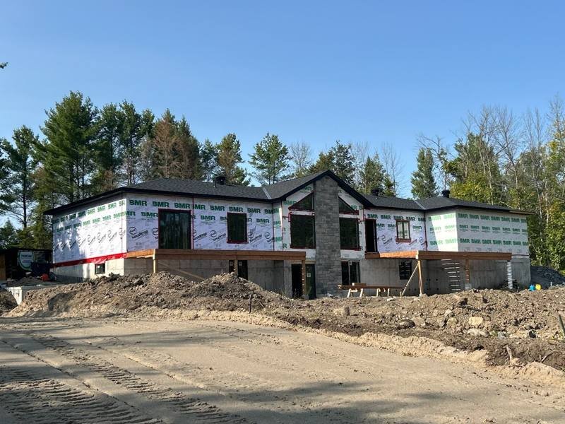 Custom home framed by TrueCon, roof on and stone facade underway