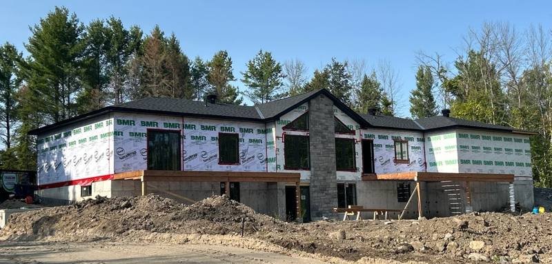 Custom home framed by TrueCon, roof on and stone facade underway