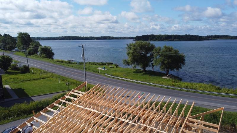 Roof rafters on a waterfront custom home, with the river behind